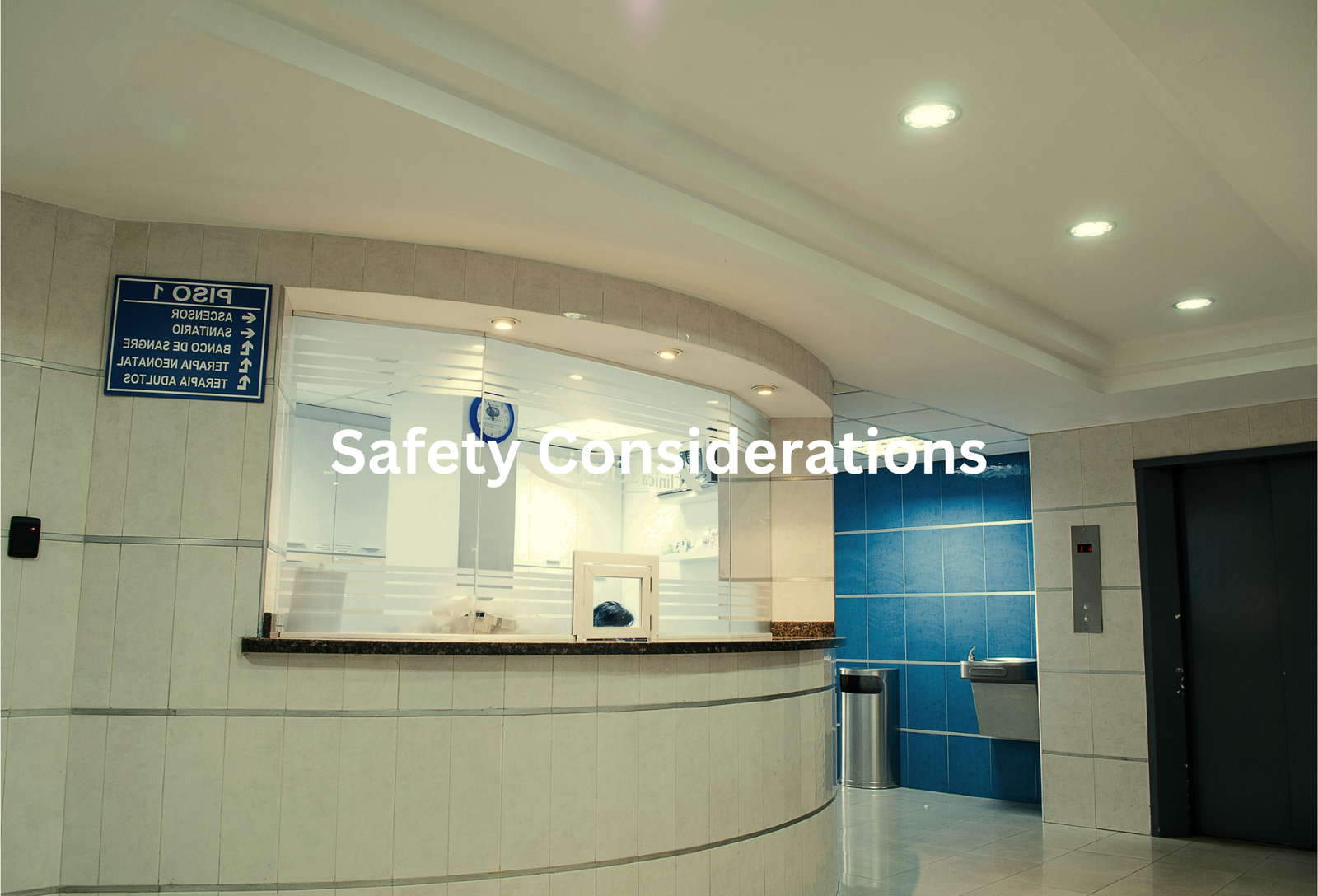 Interior of a facility with a Safety Considerations sign and a reception desk with a blue tiled wall behind it